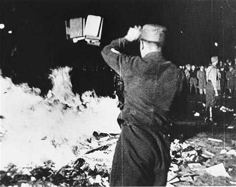 A man tosses another book onto a burning pile of material from Magnus Hirschfeld's Institut für Sexualwissenschaft